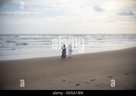 Zwei Frauen, Die Am Ruhigen Sandstrand Entlang Laufen Stockfoto