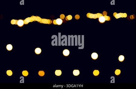 Bokeh-Lichter leuchten nachts. Goldene Punkte bilden abstrakte Muster mit verschwommener Brillanz, traumhafter Glitzerstimmung und festlicher Schimmer-Atmosphäre. Radien Stockfoto
