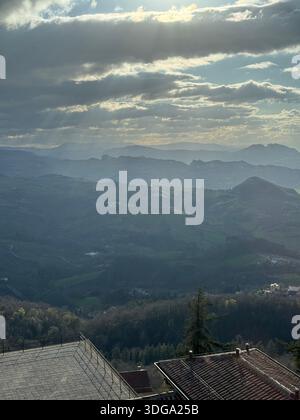 Geschichtete Hügel und nebelige Berge unter einem leuchtenden Himmel in der Landschaft von San Marino Stockfoto