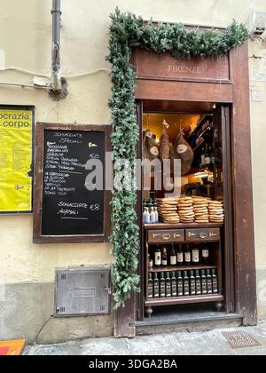 Eingang eines traditionellen Lebensmittelgeschäfts in Florenz, Italien, mit lokalen toskanischen Spezialitäten, Weinflaschen und Wurstwaren in einer bezaubernden historischen Straße Stockfoto