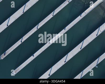 Aus der Vogelperspektive auf die Betonpiers des Yachthafens, die durch das tiefe türkisfarbene Wasser schneiden, Ocean Reef, Western Australia, Australien. Stockfoto