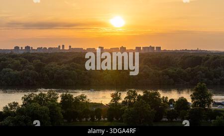 Blick auf die Donau bei Sonnenuntergang am Zusammenfluss mit der Save in Belgrad, Serbien, üppige grüne Bäume und die Skyline von Belgrad, Blick vom Kalemegdan Park Stockfoto