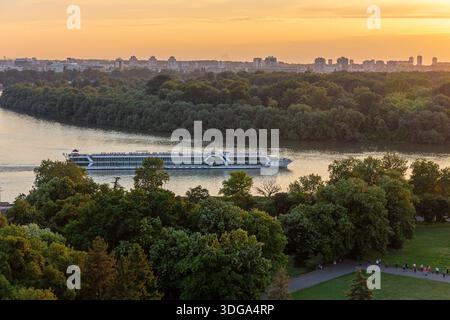 Belgrad, Serbien, 13.06.22. Flussschiff Amadeus elegant navigiert auf der Donau in Belgrad, Serbien mit der Skyline der Stadt im Hintergrund, Sonnenuntergang Stockfoto