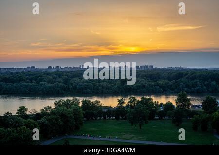 Blick auf die Donau bei Sonnenuntergang am Zusammenfluss mit der Save in Belgrad, Serbien, üppige grüne Bäume und die Skyline von Belgrad, Blick vom Kalemegdan Park. Stockfoto