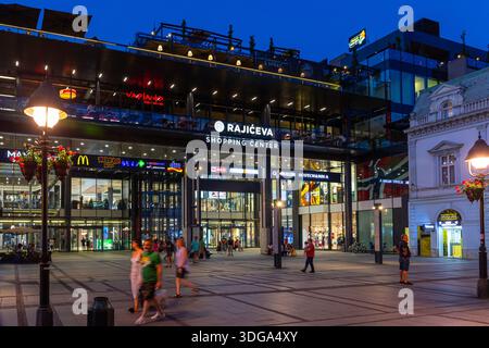 Belgrad, Serbien, 13.06.22. Rajiceva Shopping Center in Belgrad, Serbien, Nachtblick mit beleuchteter Außenfassade des Einkaufszentrums mit Menschen Stockfoto
