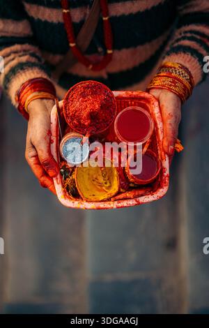 Blick auf die Hände, die ein Tablett mit lebendigen bunten Pulvern und Flüssigkeiten halten, eine Feier der Kultur und Tradition, Himalaya, Annapurna, Nepal. Stockfoto
