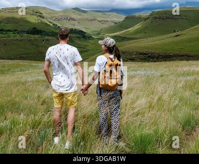 Ein Paar genießt einen ruhigen Moment, während es Hände im hohen Gras des Drakensberg Giant Castle in Südafrika hält. Stockfoto