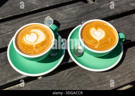 Eine Tasse Kaffee mit herzförmiger Latte Art, serviert in grüner Keramikschale und Untertasse Stockfoto