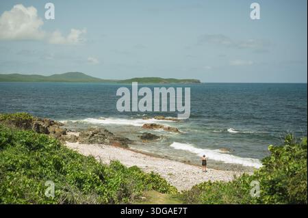 Frau im Ruhestand am felsigen Strand mit Blick auf das Meer in Vieques Stockfoto