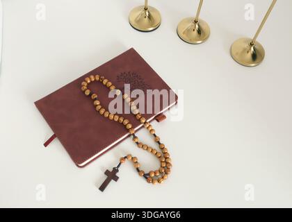Katholische Ecke zu Hause. Hölzerne Rosenkranzperlen, Kreuz und Gebetsbuch. Glaube, Symbole und Traditionen. Stockfoto