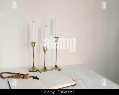 Katholische Ecke zu Hause. Hölzerne Rosenkranzperlen, Kreuz und Gebetsbuch. Glaube, Symbole und Traditionen. Stockfoto