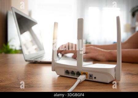 Person, die einen modernen wlan-Router auf einem Leuchttisch im Wohnzimmer verbindet Stockfoto