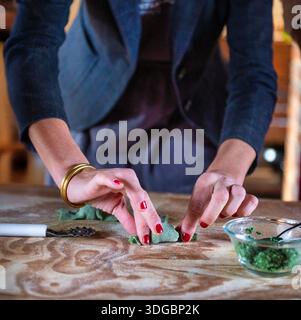 Hausgemachter grüner Nudelteig auf einem Holztisch, traditionelles italienisches Kochverfahren mit frischer Spinat-Pasta-Zubereitung. Stockfoto