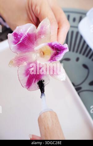 Violette und weiße Orchidee werden während des Herstellungsprozesses der Werkstatt für Heimwerkerzubehör in mehreren Schichten Harz aufgetragen Stockfoto