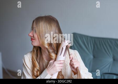 Happy Woman macht morgendliche Haarroutine drinnen, die Schönheit und Selbstpflege-Lifestyle-Konzept zeigt Stockfoto