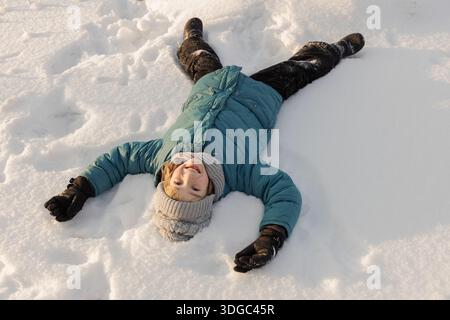 Glückliches Kind liegt an einem frostigen sonnigen Tag im Schnee. Stockfoto