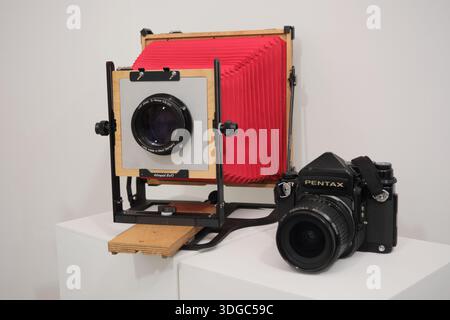 Seoul, Südkorea: Großformatige Holzkamera mit rotem Balg neben einer klassischen Pentax Mittelformatkamera in der Fotoausstellung Stockfoto