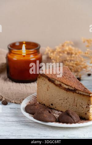 Gemütliche Dessertszene mit einem Stück Käsekuchen mit Kaffeegeschmack und mit Kakao verstaubten Trüffeln auf einem rustikalen Hintergrund Stockfoto
