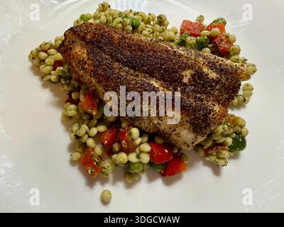 Gebratener Branzino mit Couscous-Salat in der Pfanne. Stockfoto