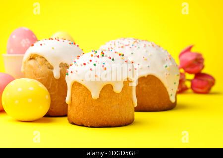 Köstliche Osterkuchen, Eier und Tulpen auf gelbem Hintergrund, Nahaufnahme Stockfoto