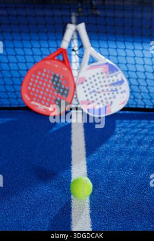 Fokussierter Ball auf der Hallenpadel-Court-Linie mit Schlägern, die sich auf das Netz stützen, für die Turnierförderung und sauberen Kopierraum Stockfoto
