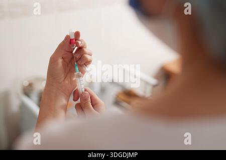 Eine Ärztin zieht ein Medikament in eine Spritze, selektiver Fokus. Stockfoto