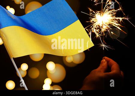 Ukrainisches Weihnachtsgrußkartendesign mit Nationalflagge. Brennender Glitzer und Bokeh-Lichter auf schwarzem Hintergrund Stockfoto