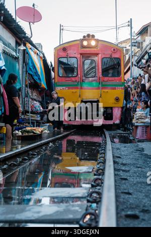 Maeklong Railway Market in Thailand, 5. Dezember 2025, als ein Zug durch pulsierende Stände fährt. Dieser einzigartige Markt verbindet das tägliche Leben mit Touristen Stockfoto