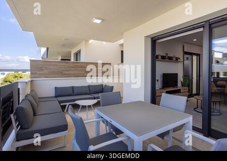 Geräumige Außenterrasse mit Sitz- und Essbereich, verbunden mit stilvollem Wohnzimmer Stockfoto