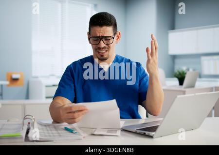 Gestresster Buchhalter Prüft Schockierende Rechnungen Auf Laptop In Seinem Büro. Stockfoto