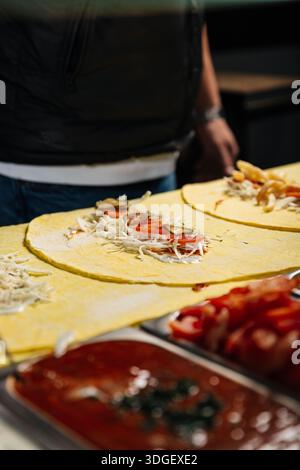 Eine offene Schawarma in voller Größe auf Fladenbrot zeigt alle Zutaten – Fleisch, Gemüse und Saucen – gleichmäßig vor dem Umwickeln an. Stockfoto