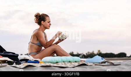 Junge gebräunte Frau beim Abendessen am Strand Stockfoto