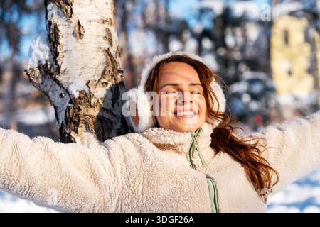 Fröhliche junge Frau, die den Winter im Freien genießt Stockfoto