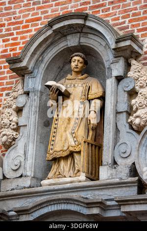 Eine Statue des Heiligen Stephans in einer bogenförmigen Steinnische, oberhalb des Eingangs zur St. Stephans Kirche in Gent, Belgien Stockfoto