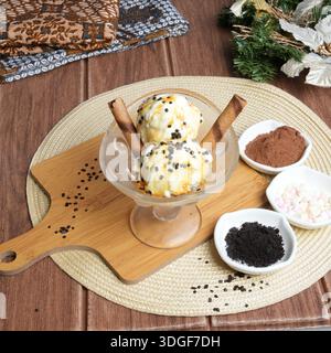 Zwei Kugeln Vanilleeis mit Karamell- und Schokoladenstreuseln, serviert in einem Eisbecher aus Glas. Stockfoto