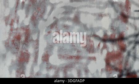 Verschwommenes Bild von chaotischen Linien und Spritzern weißer Farbe auf einer rötlich metallisch oxidierten Oberfläche, abstrakte, glatte Textur als Rohling Stockfoto