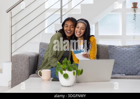 Verschiedene Mom und Teenager-Tochter bewerten Farbmuster mit offenem Laptop, der auf dem Sofa sitzt Stockfoto