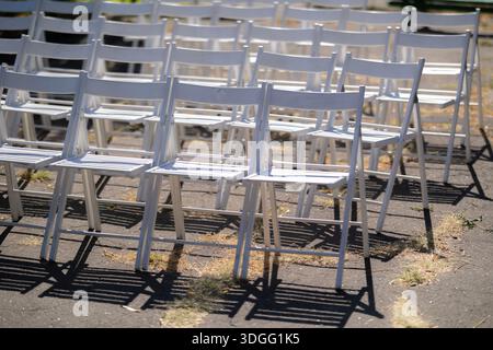Reihen weißer Stühle stehen im Freien in einem Park, bereit für ein Open-Air-Musikkonzert. Stockfoto
