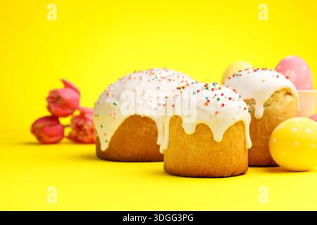 Köstliche Osterkuchen, Eier und Tulpen auf gelbem Hintergrund Stockfoto