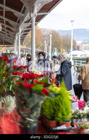 Bilbao, Spanien – 21. November 2021: Zwei Frauen, die Schutzmasken tragen, durchstöbern im offenen Ai eine lebhafte Auswahl an Blumen, darunter rote Weihnachtsbäume Stockfoto