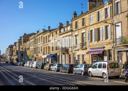 Bordeaux, Frankreich - 23. November 2021: Klassische Gebäude säumen eine Stadtstraße mit Straßenbahngleisen, mit Straßenlaterne und klarem Himmel. Bordeaux, Gironde, Nein Stockfoto