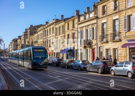 Bordeaux, Frankreich - 23. November 2021: Klassische Gebäude säumen eine Stadtstraße mit Straßenbahngleisen, mit Straßenlaterne und klarem Himmel. Bordeaux, Gironde, Nein Stockfoto
