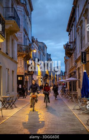 Bordeaux, Frankreich - 23. November 2021: Abendliche Straßenszene auf der Rue du Ha, einer Straße, die nur für Fahrräder genutzt wird, mit beleuchteten Straßenlaternen, mit Radfahrern und Fußgängerzonen Stockfoto