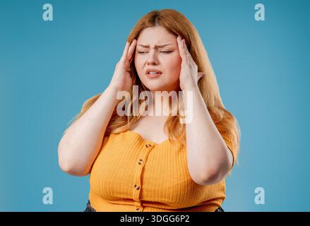 Plus Size Frau, Die Tempel Berührt, Leidet An Kopfschmerzen, Pink Studio. Schmerzen. Stockfoto