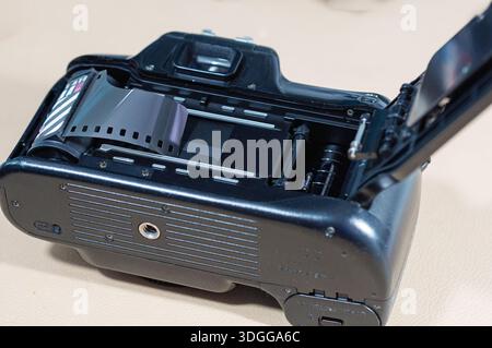 Eine Rolle Schwarzweißfilm wird in eine offene 35-mm-Filmkamera geladen, die einsatzbereit ist. Nostalgie für alte Technik Stockfoto