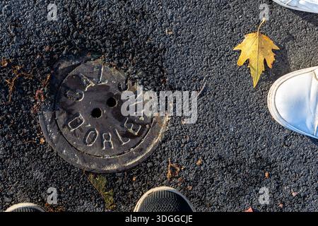 Runder Metalldeckel mit Text Gaz d Orleans auf Asphaltstraße. Städtische Luke in Orleans Frankreich mit gelbem Herbstblatt und s Stockfoto