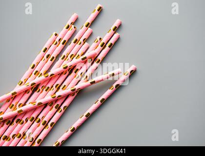 Trinkhalme mit Punktmuster für Party auf grauem Hintergrund mit Kopierraum. Blick von oben auf farbenfrohe, umweltfreundliche Einweg-Strohhalme aus Papier für Sommer-Cocktails. Stockfoto