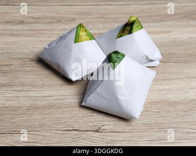 Traditionelle Packungen von Nasi-Lemak in Bananenblatt und Papier auf Holztischhintergrund gewickelt Stockfoto