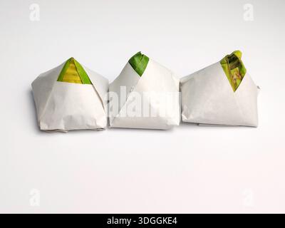 Drei Packungen traditioneller malaysischer Nasi-Lemak, verpackt in Papier und Bananenblatt auf weißem Hintergrund Stockfoto