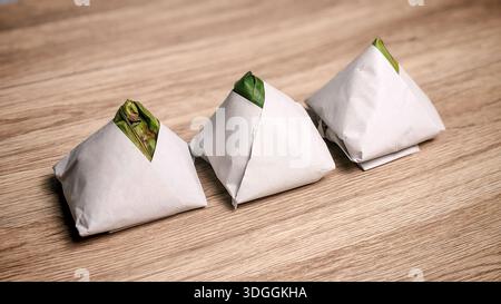 Traditionelle Packungen von Nasi-Lemak in Bananenblatt und Papier auf Holztischhintergrund gewickelt Stockfoto